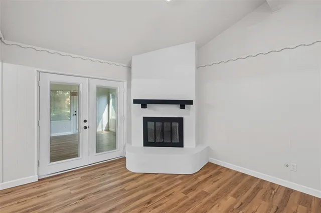 a view of an empty room with wooden floor and a fireplace