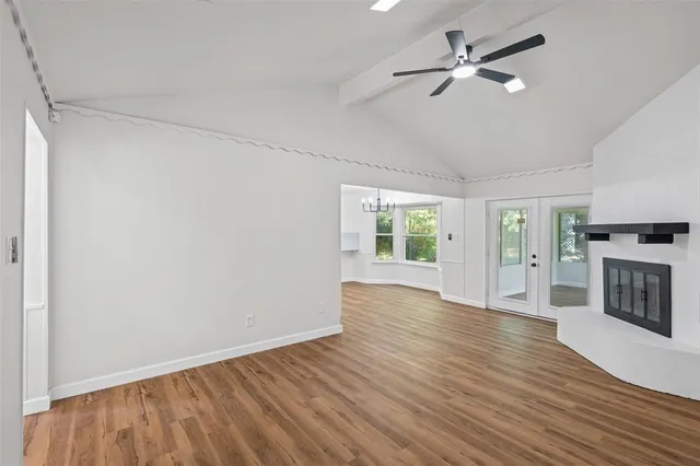 an empty room with wooden floor fireplace and windows