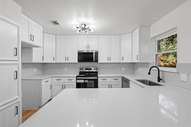 a kitchen with stainless steel appliances a sink a stove a microwave and cabinets
