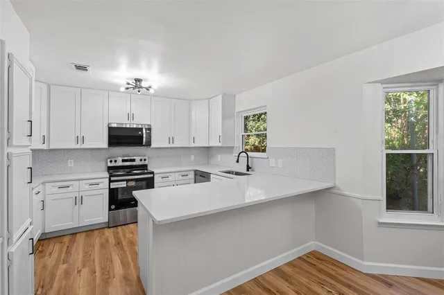 a kitchen with stainless steel appliances a sink a stove a refrigerator cabinets and a window