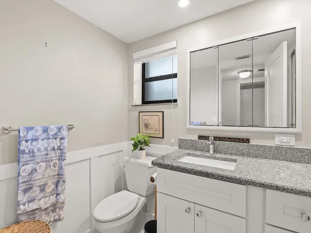 a bathroom with a granite countertop toilet sink and mirror