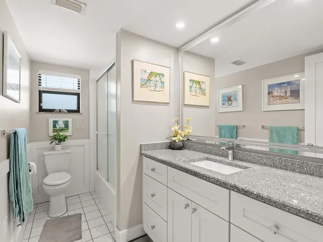 a bathroom with a granite countertop sink mirror and toilet