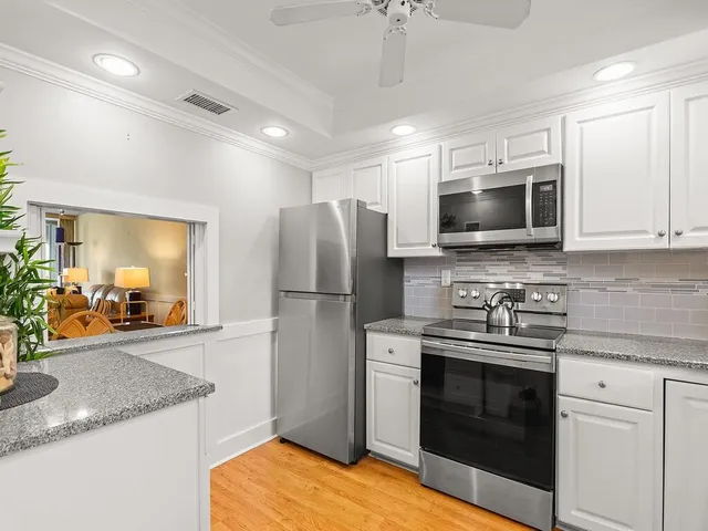 a kitchen with stainless steel appliances granite countertop a stove a microwave a refrigerator a sink and dishwasher with wooden floor