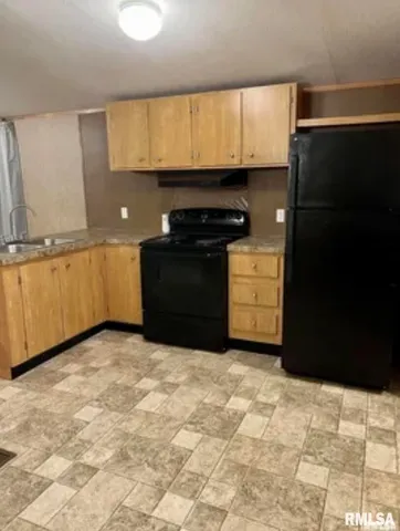 a kitchen with granite countertop a stove a sink and a refrigerator