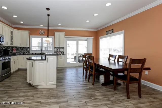 a kitchen with stainless steel appliances granite countertop wooden floor a dining table and chairs