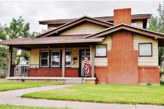 a view of a house with a yard potted plants and a table