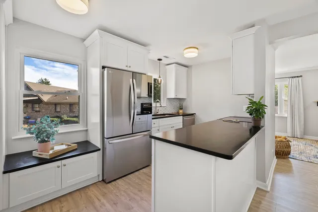 a kitchen with stainless steel appliances granite countertop a refrigerator a sink a stove and a wooden floors