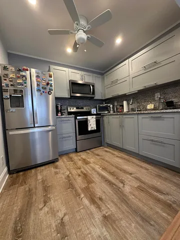 a large kitchen with stainless steel appliances granite countertop a refrigerator a stove a sink and a microwave