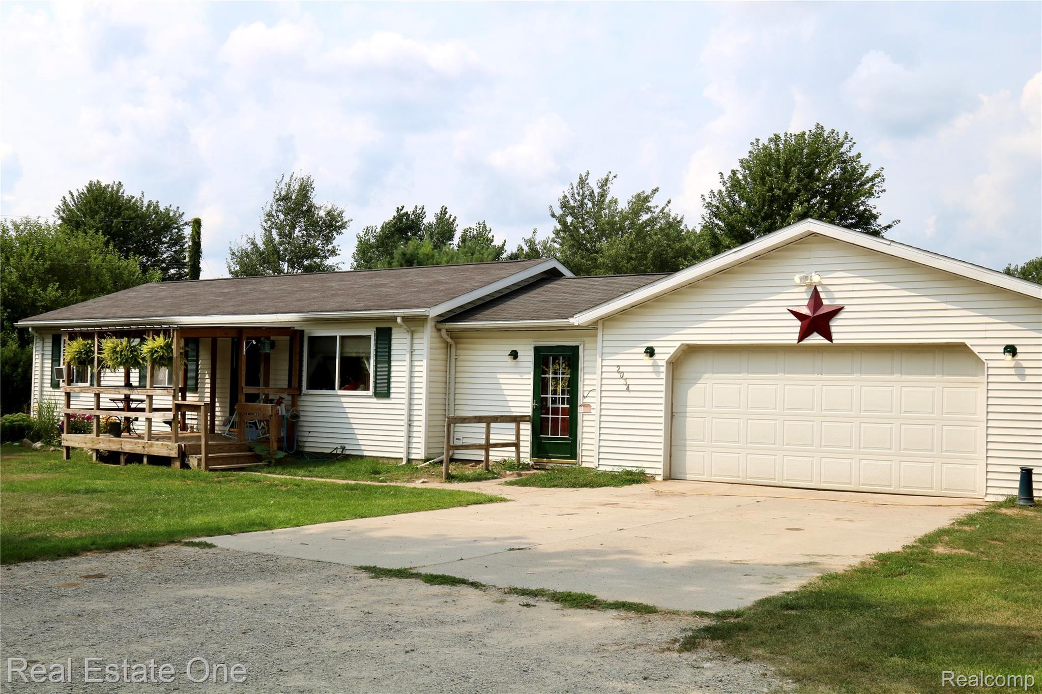 Light-colored siding exterior with a covered porch, attached two-car garage, and asphalt shingle roofing