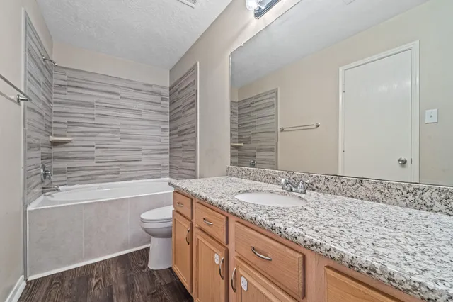 a bathroom with a granite countertop sink toilet and shower