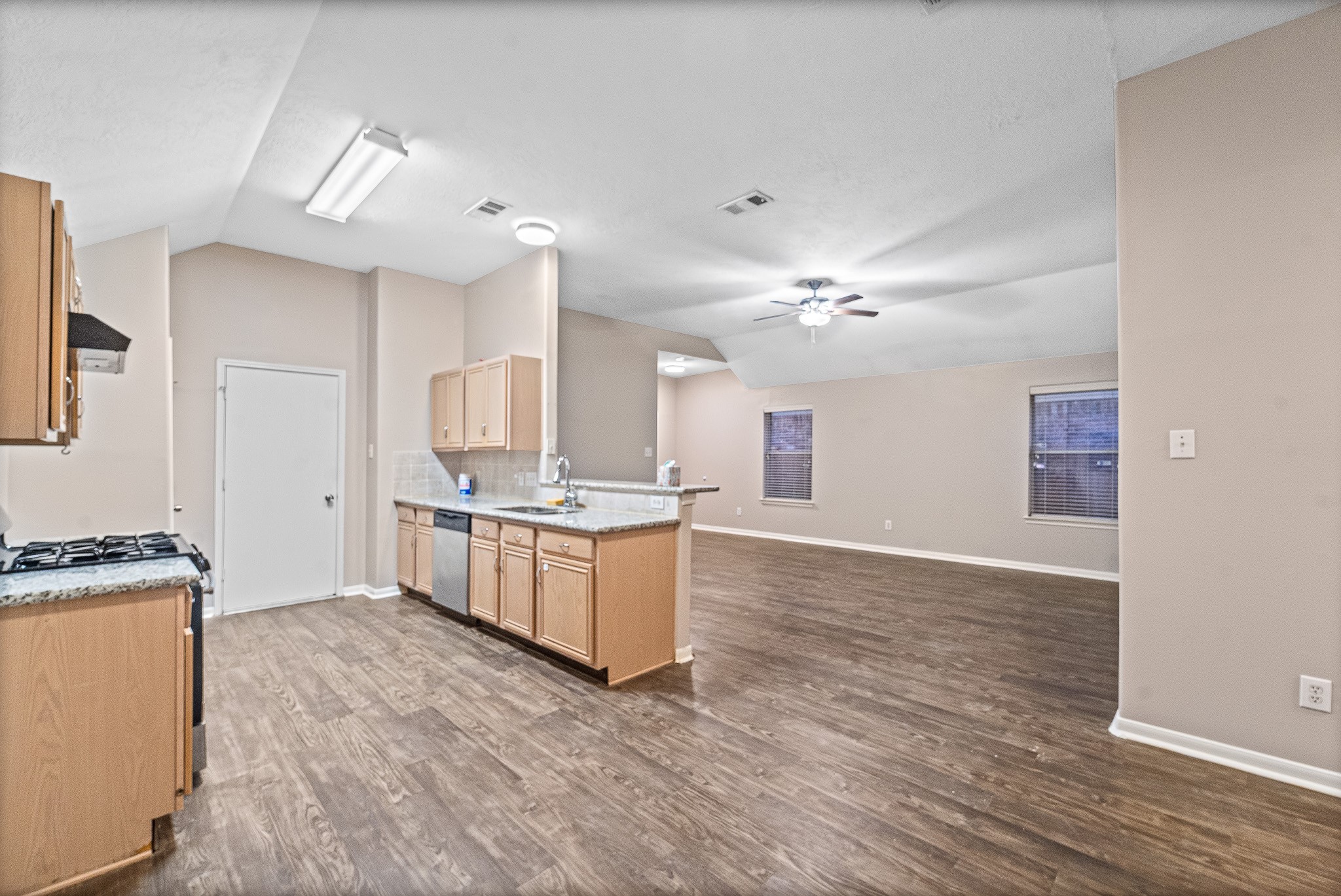 6827 Highwind Bend Lane Katy, TX 77449 - Photo 7 of 20 a large kitchen with kitchen island a stove a sink a refrigerator white cabinets and wooden floor