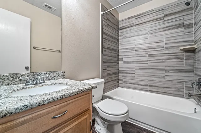 a bathroom with a granite countertop bathtub sink vanity mirror and toilet