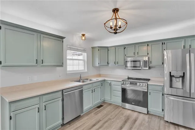 a kitchen with stainless steel appliances a sink cabinets and a window