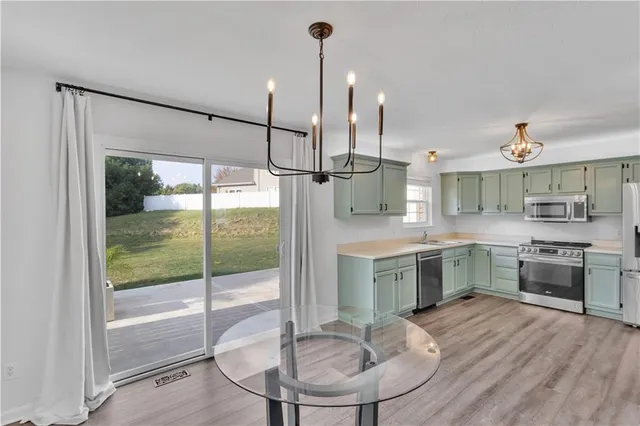 a kitchen with kitchen island a large counter top space appliances and a view of living room