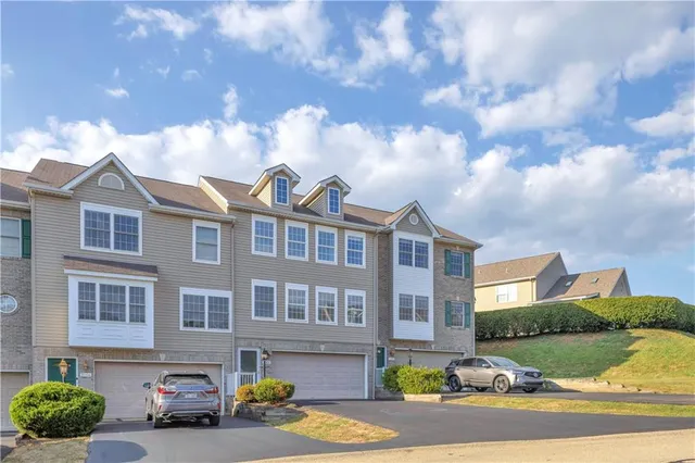 a front view of a residential apartment building with yard and parking spaces
