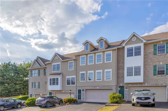 a front view of a residential apartment building with cars parked