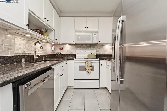a white kitchen with a sink and refrigerator