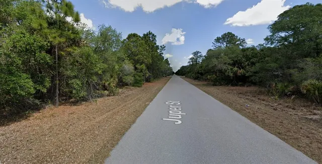 a view of a street with a house in the background