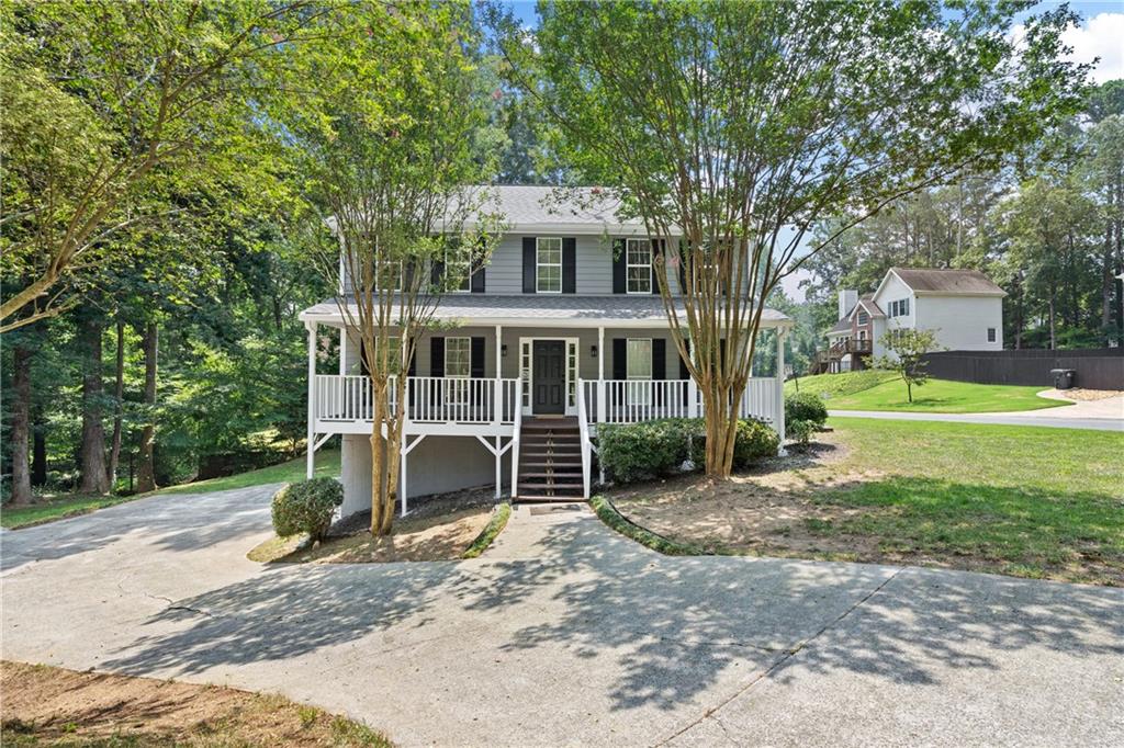 a view of a house with a yard and large tree