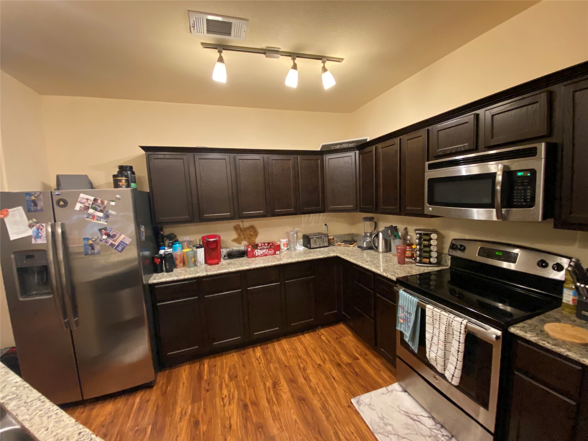 1239 20th Street, Unit B Huntsville, TX 77340 - Photo 7 of 17 a kitchen with granite countertop a refrigerator stove and microwave