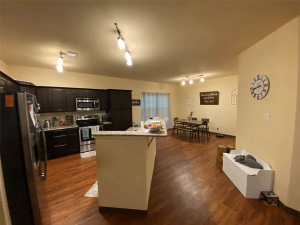 a living room with couches kitchen view and a refrigerator