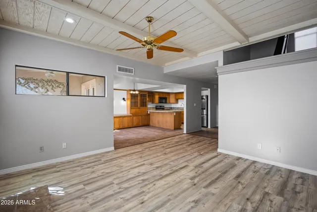 a view of an empty room with a window and wooden floor