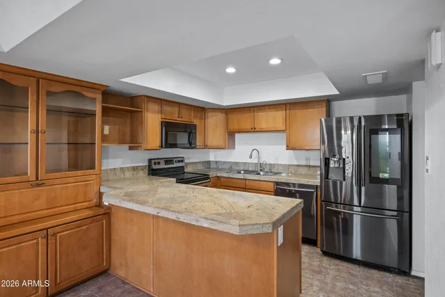 a kitchen with stainless steel appliances granite countertop a refrigerator a stove and a sink with wooden floor