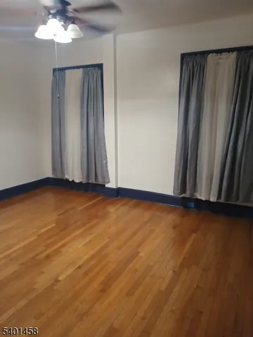 an empty room with wooden floor and chandelier fan