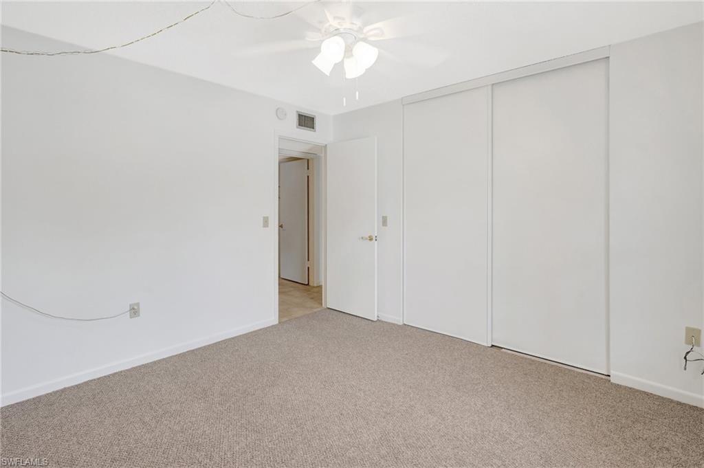 151 Cypress Way East, Unit D3 Naples, FL 34110 - Photo 14 of 46 Unfurnished bedroom with a closet, visible vents, baseboards, ceiling fan, and light carpet