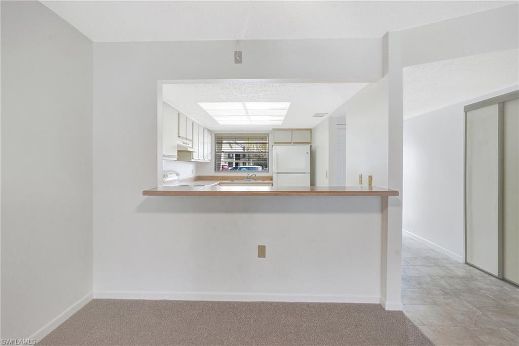 151 Cypress Way East, Unit D3 Naples, FL 34110 - Photo 18 of 46 Kitchen with freestanding refrigerator, light carpet, a peninsula, stove, and under cabinet range hood