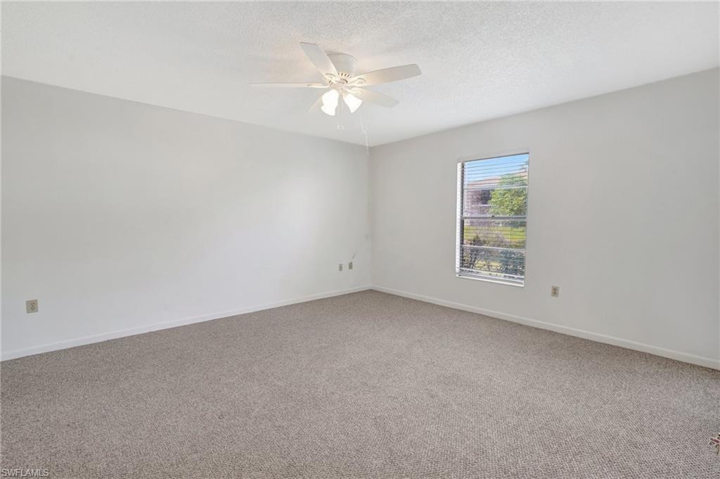 151 Cypress Way East, Unit D3 Naples, FL 34110 - Photo 24 of 46 Unfurnished room with a textured ceiling, baseboards, light colored carpet, and ceiling fan