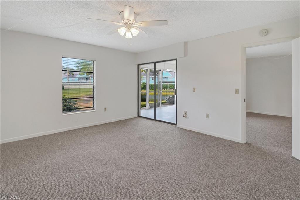 151 Cypress Way East, Unit D3 Naples, FL 34110 - Photo 27 of 46 Unfurnished room featuring a textured ceiling, ceiling fan, carpet floors, and a healthy amount of sunlight