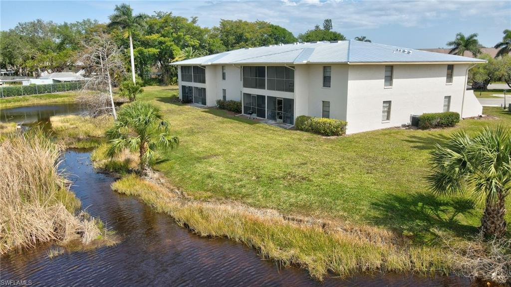 151 Cypress Way East, Unit D3 Naples, FL 34110 - Photo 39 of 46 Rear view of property with metal roof, stucco siding, and a yard