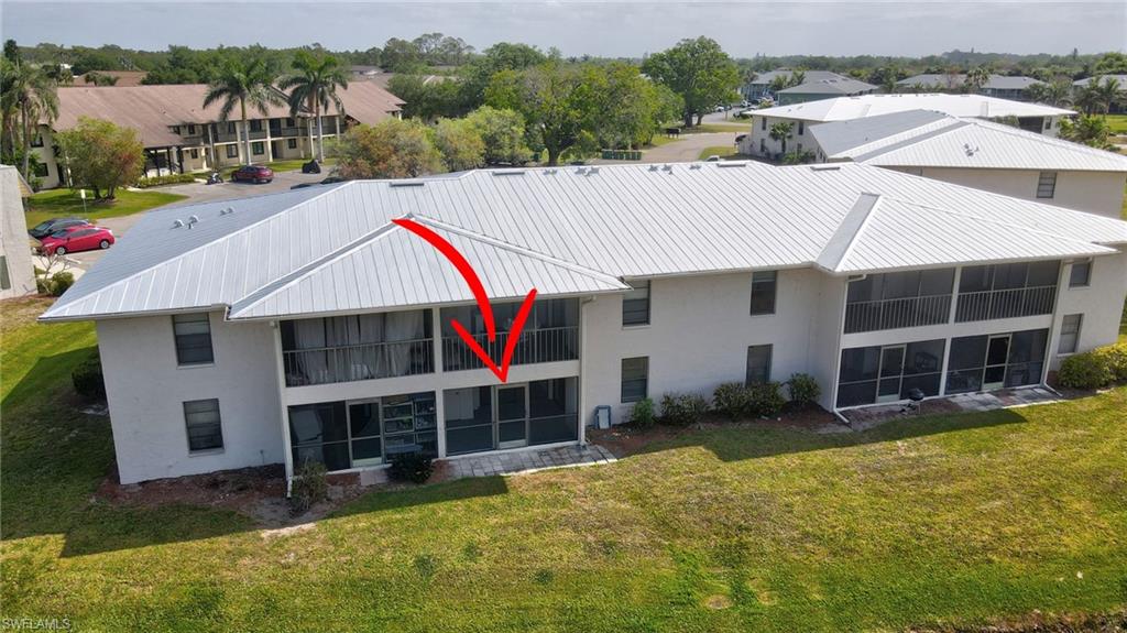 151 Cypress Way East, Unit D3 Naples, FL 34110 - Photo 40 of 46 Rear view of house featuring a sunroom, stucco siding, a yard, and metal roof