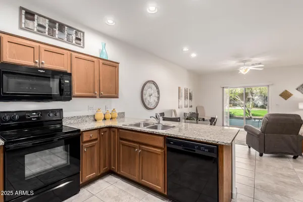 a kitchen with granite countertop a sink cabinets stainless steel appliances and a window