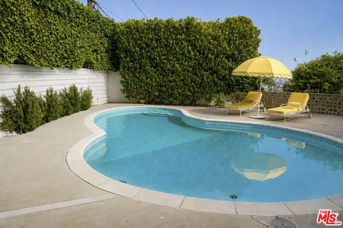 a view of a swimming pool with a table and chairs under an umbrella
