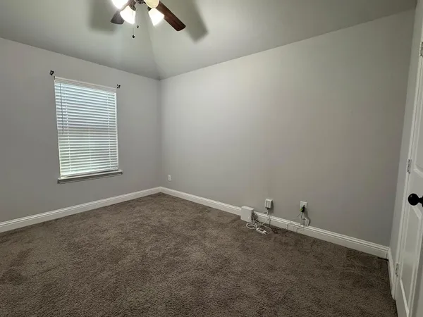 an empty room with a chandelier fan and windows