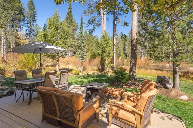 a view of a patio with table and chairs under an umbrella with large trees