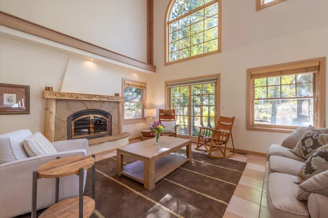 a living room with furniture a fireplace and a floor to ceiling window
