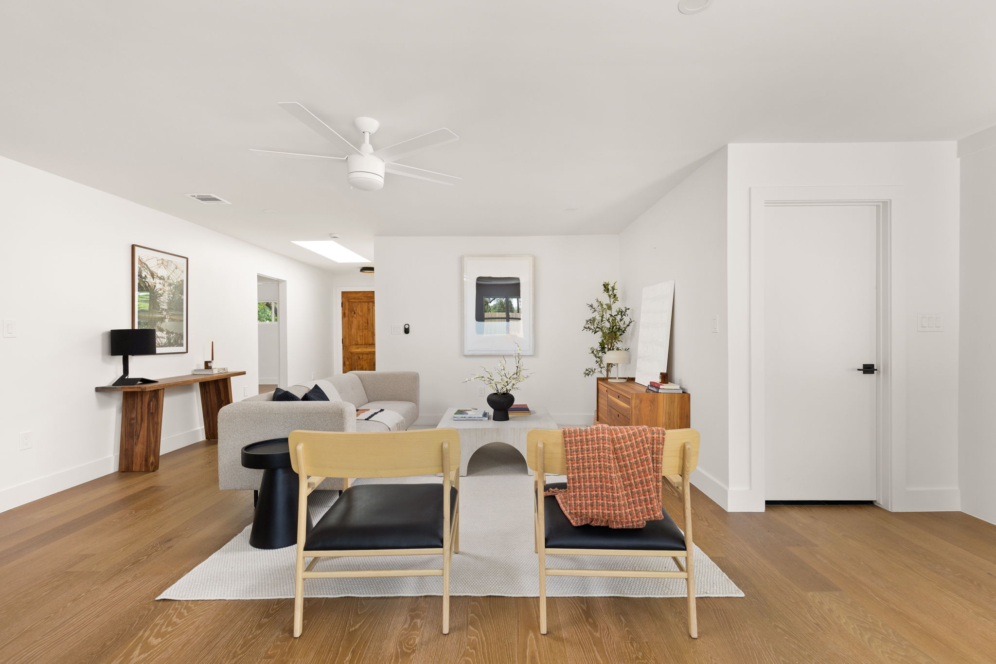 4501 Pack Saddle Pass Austin, TX 78745 - Photo 8 of 37 Bright living area featuring wood-finish flooring, crisp white walls, a modern ceiling fan, and a skylight