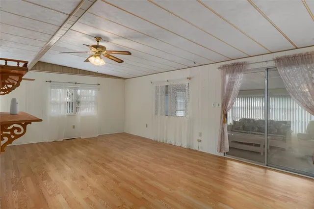 a view of empty room with wooden floor and fan
