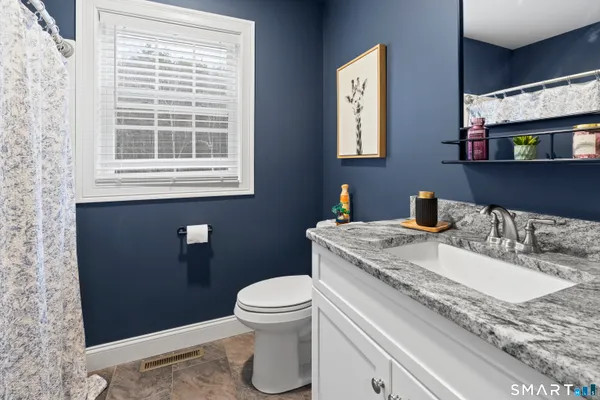 a bathroom with a granite countertop toilet sink and mirror