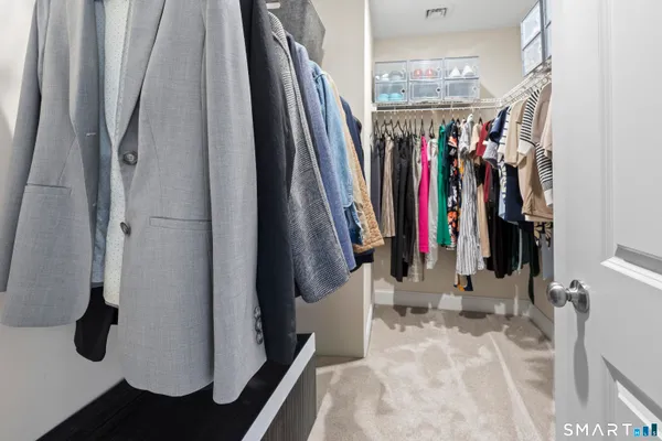 a view of walk in closet with clothes and shoes