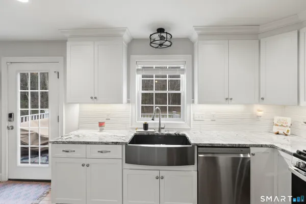 a kitchen with granite countertop a sink stove and cabinets