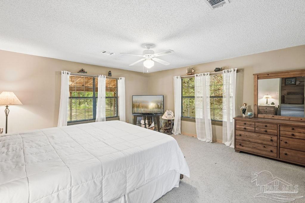 8938 Pioneer Road Holt, FL 32564 - Photo 17 of 44 a spacious bedroom with a large bed and a dresser