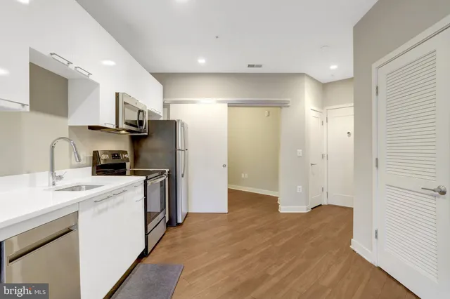 a kitchen with a sink a counter top space stainless steel appliances and cabinets