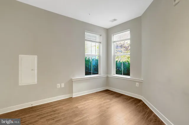 an empty room with wooden floor and windows