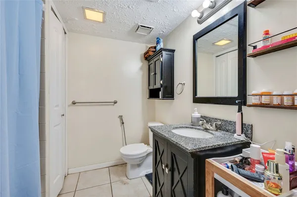 a bathroom with a granite countertop sink a toilet and mirror