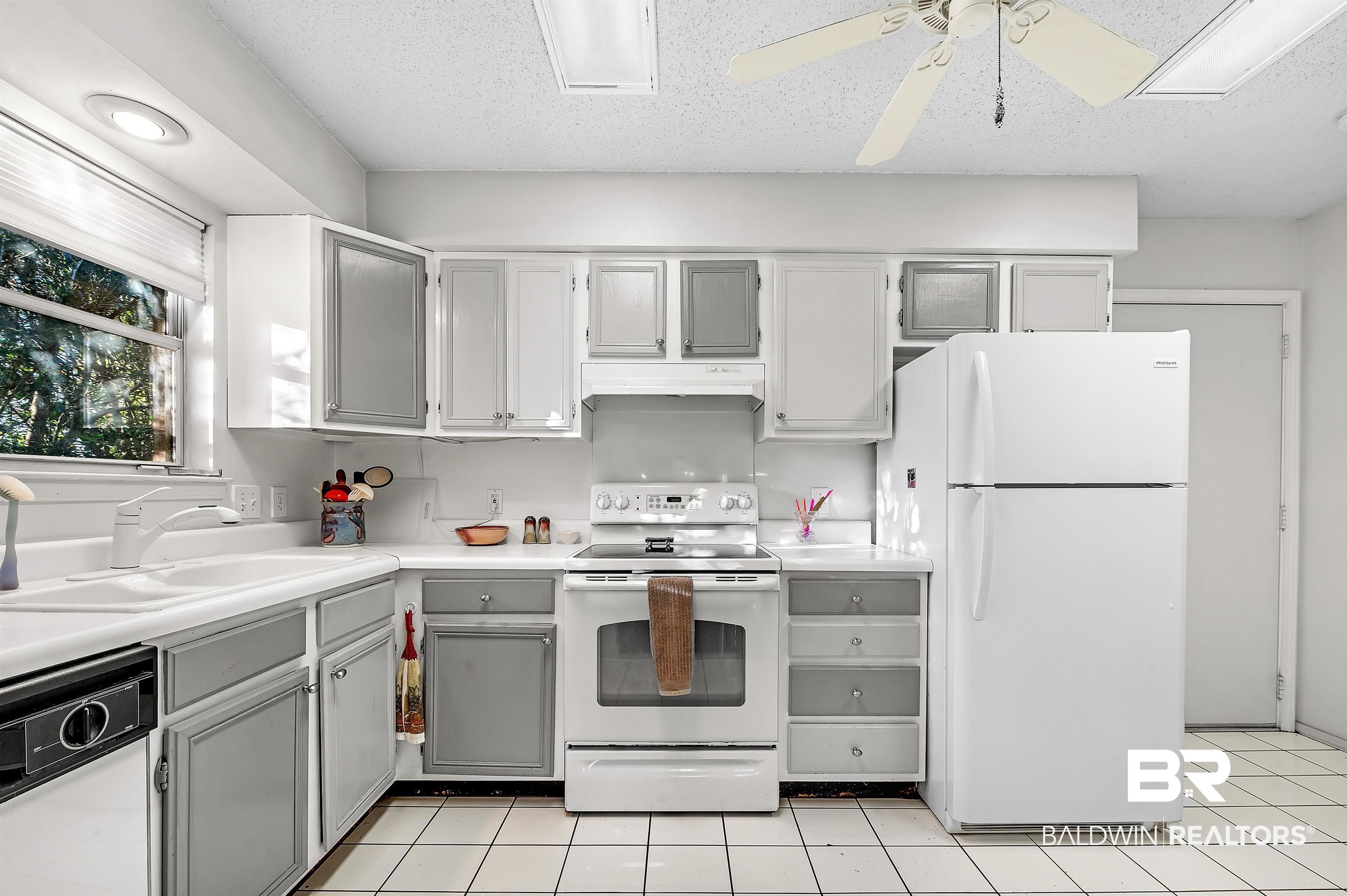 526 Ariel Avenue Foley, AL 36535 - Photo 17 of 33 Kitchen with gray cabinetry, sink, white appliances, and a textured ceiling