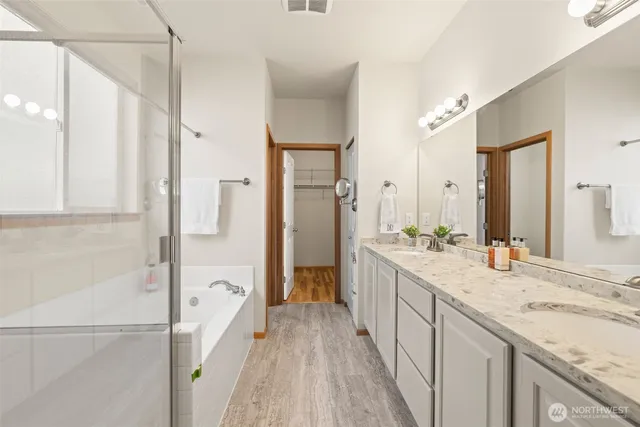 a bathroom with a sink double vanity granite tub and a mirror